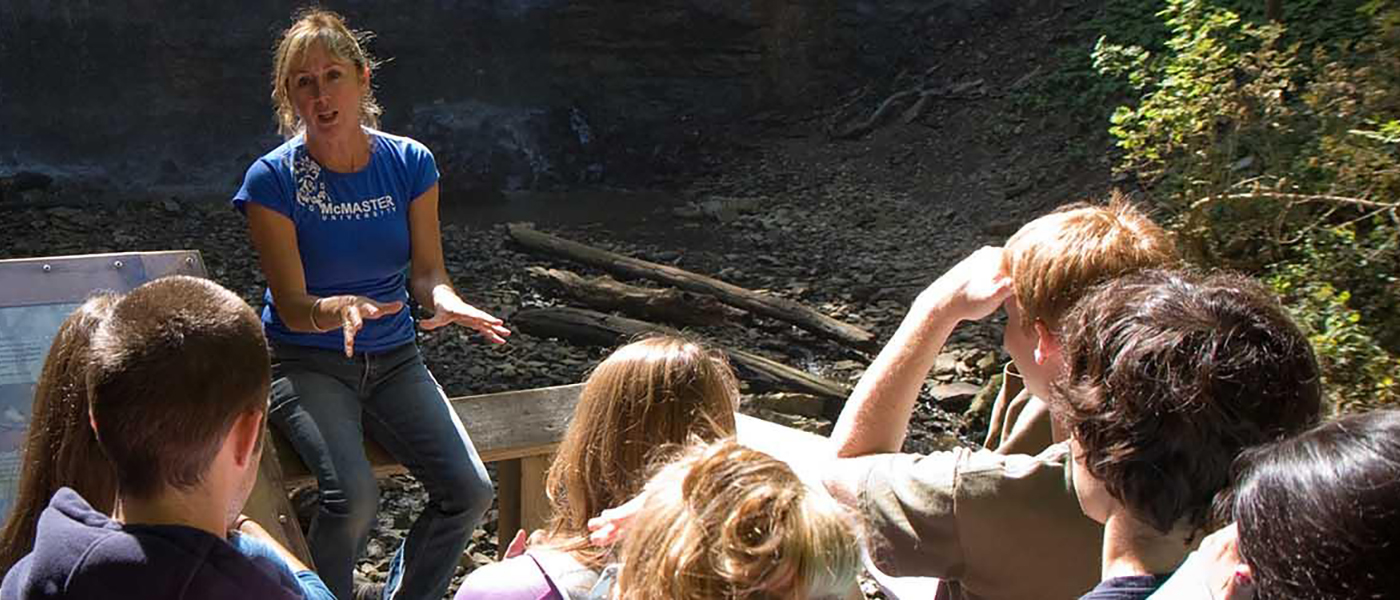 An instructor speaking to a group of students outdoors.